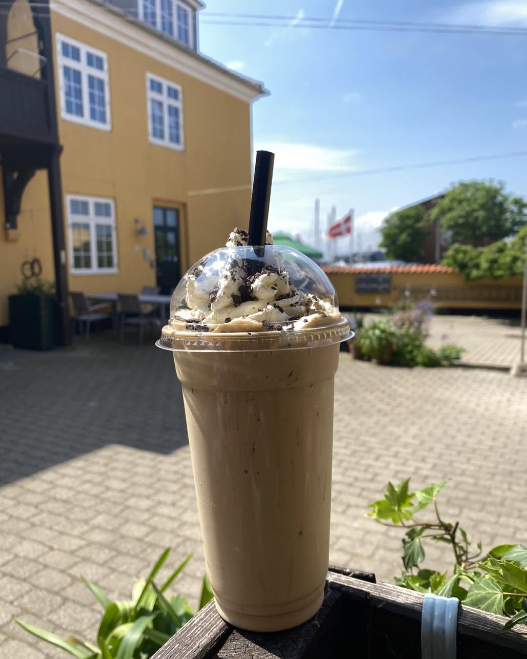 Iskaffe med flødeskum og chokolade foran det gule hus